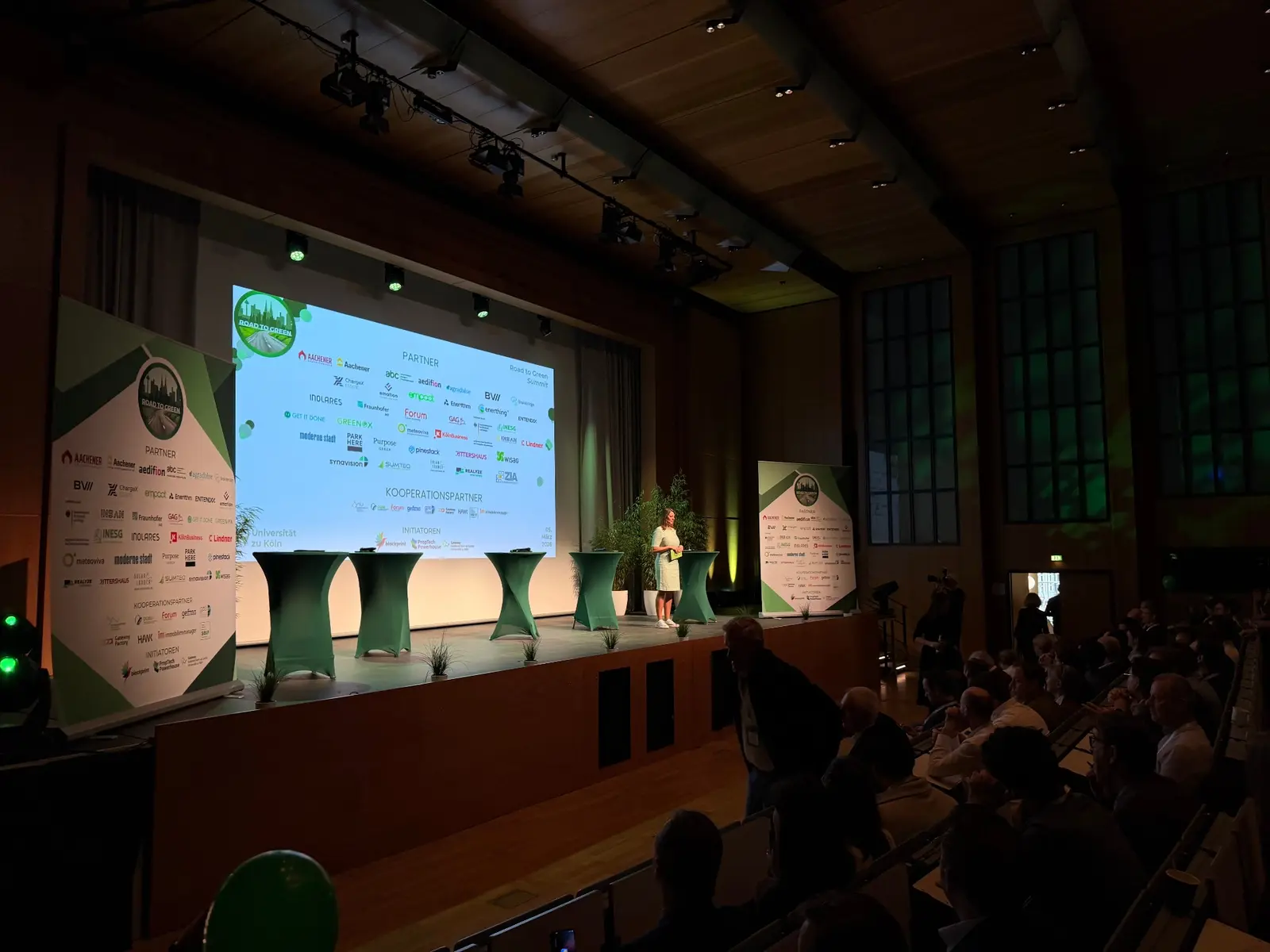 Eröffnung des Road to Green Summit 2026 in der Universität zu Köln, Bühne mit Partner- und Initiatoren-Wall